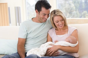 Couple in living room with baby smiling